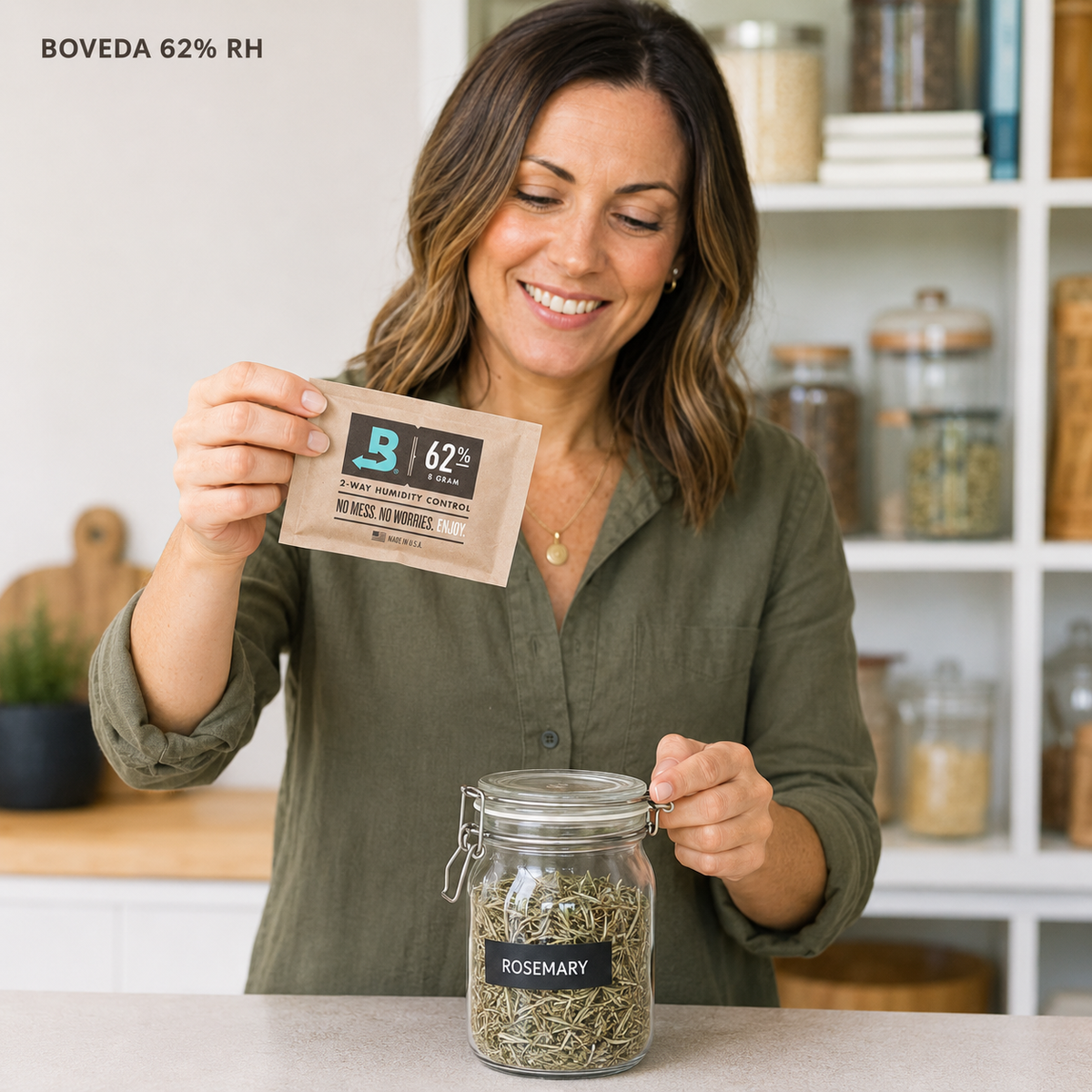 Adult Australian woman presenting a Boveda 62% RH 8g humidity pack beside a sealed jar of dried culinary rosemary.